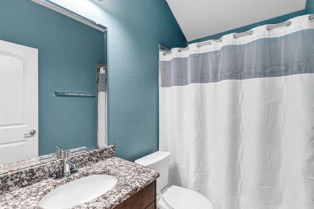 full bath with vanity, a shower with curtain, toilet, lofted ceiling, and a textured wall