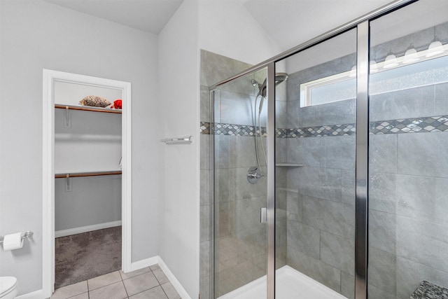bathroom with toilet, tile patterned flooring, baseboards, and a stall shower