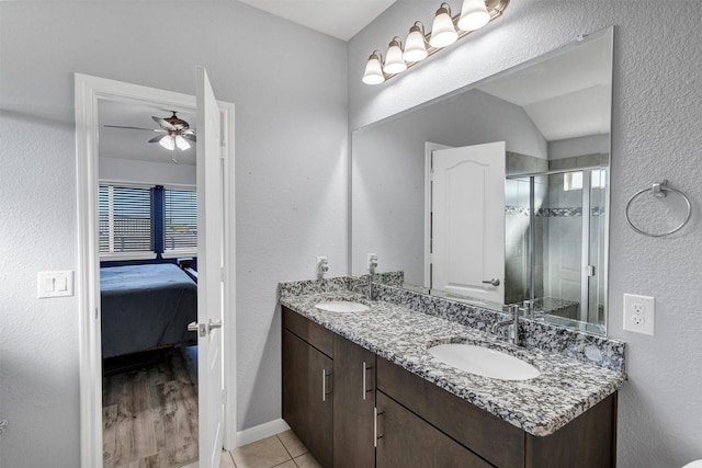 full bath with a sink, a ceiling fan, a stall shower, and double vanity