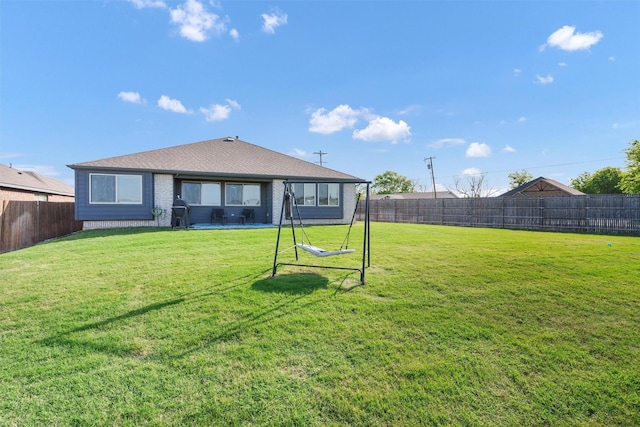 rear view of house featuring brick siding, a fenced backyard, and a lawn