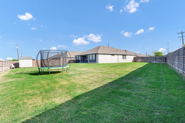 view of yard with a storage shed, a fenced backyard, a trampoline, and an outdoor structure
