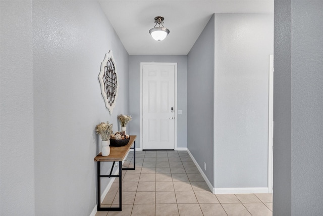 interior space with baseboards, light tile patterned flooring, and a textured wall