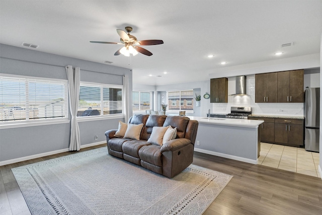 living room featuring light wood-type flooring, a ceiling fan, and visible vents