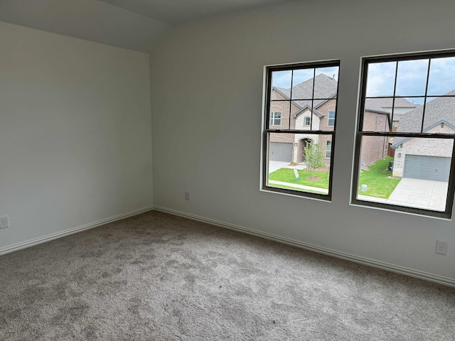 carpeted empty room with lofted ceiling and baseboards