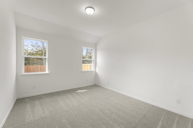 carpeted empty room with baseboards and lofted ceiling