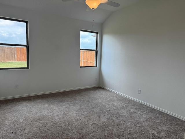 carpeted empty room with healthy amount of natural light, ceiling fan, vaulted ceiling, and baseboards