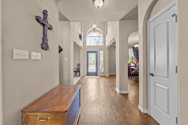 1321 Spanish Needle Trl, Fort Worth, TX 76177 - entrance foyer with a chandelier, arched walkways, dark wood-type flooring, and baseboards