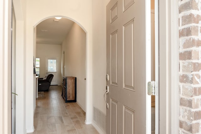 corridor with baseboards, visible vents, and arched walkways