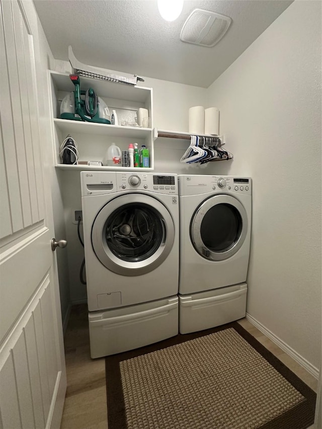 laundry room with visible vents, washing machine and clothes dryer, baseboards, and laundry area