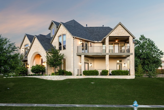 2413 Versailles Dr, Heath, TX 75032 - view of front facade with a balcony, stone siding, a lawn, and roof with shingles
