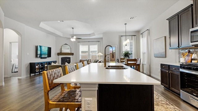 kitchen featuring dark wood finished floors, stainless steel gas range oven, light countertops, and a sink
