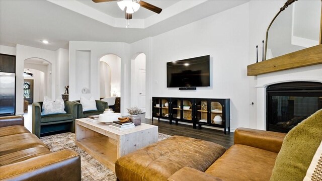 living area with arched walkways, a glass covered fireplace, recessed lighting, wood finished floors, and ceiling fan