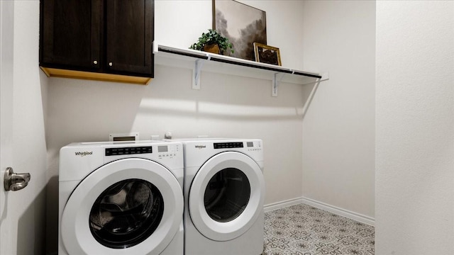 laundry room with washing machine and dryer, baseboards, and cabinet space