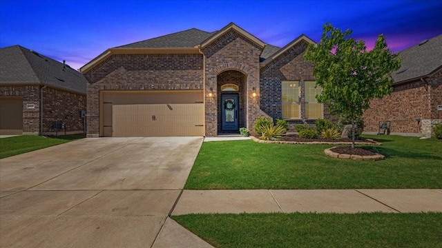 view of front of property with a lawn, driveway, brick siding, and a garage