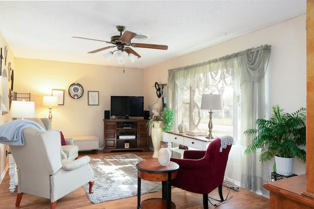 living area with a textured ceiling, wood finished floors, and a ceiling fan