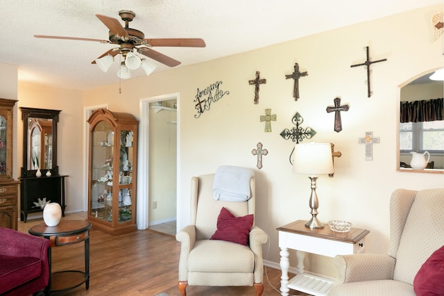 living area featuring baseboards, a ceiling fan, arched walkways, and wood finished floors