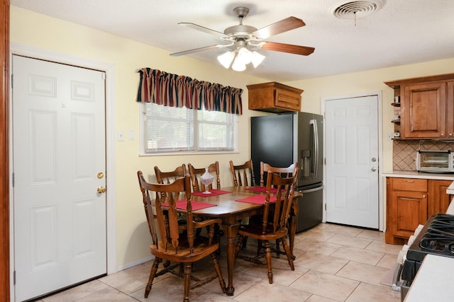 dining space with a toaster, visible vents, ceiling fan, and light tile patterned flooring