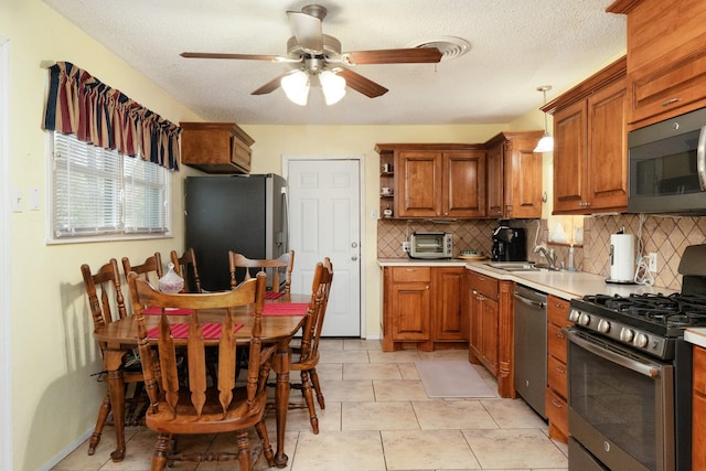 kitchen with tasteful backsplash, a sink, light countertops, a ceiling fan, and stainless steel appliances