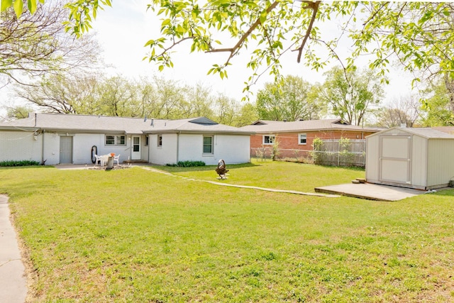 back of house featuring a fenced backyard, an outdoor structure, a lawn, a storage unit, and a patio area