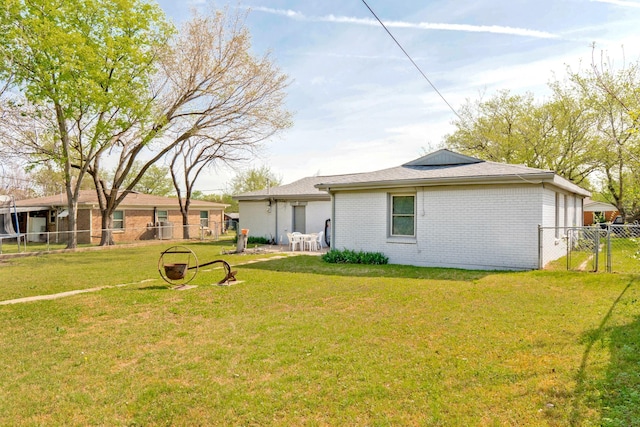 back of house with a yard, brick siding, fence, and a gate