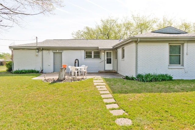 rear view of house with brick siding, a patio area, and a lawn