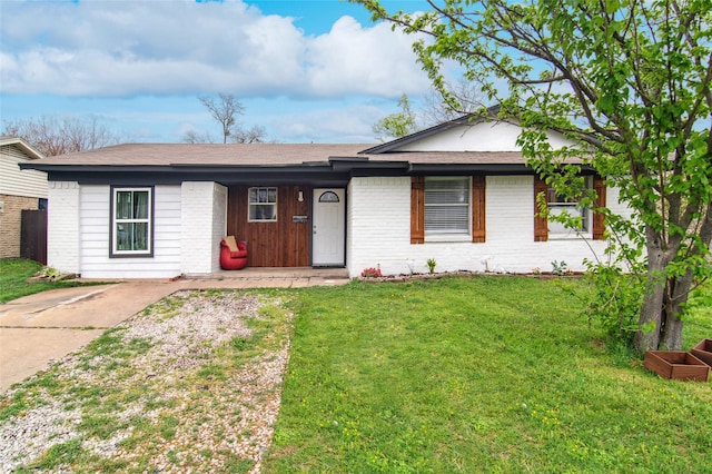 ranch-style home featuring roof with shingles, brick siding, and a front lawn