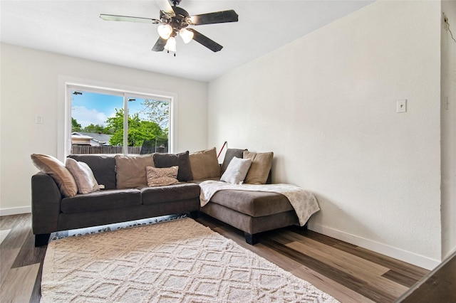 living area featuring wood finished floors, ceiling fan, and baseboards