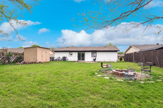 rear view of house with a fire pit, a shed, a lawn, a fenced backyard, and an outdoor structure