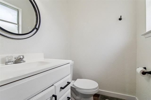 bathroom featuring toilet, wood finished floors, vanity, and baseboards