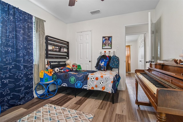 bedroom with wood finished floors, baseboards, a ceiling fan, and visible vents