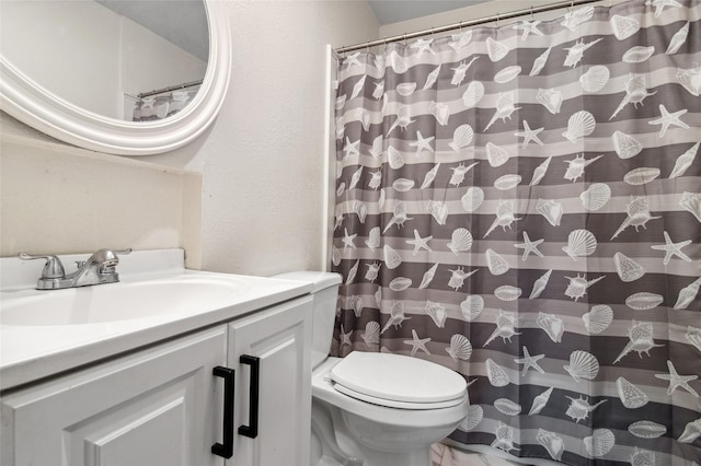 bathroom with toilet, a shower with shower curtain, vanity, and a textured wall