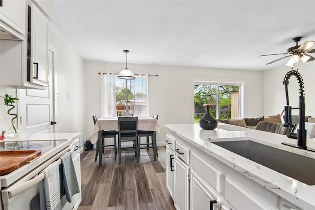 kitchen featuring light stone counters, white cabinets, white electric range, dark wood finished floors, and a sink
