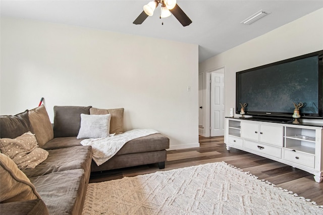 living area with dark wood-style flooring, visible vents, baseboards, and a ceiling fan