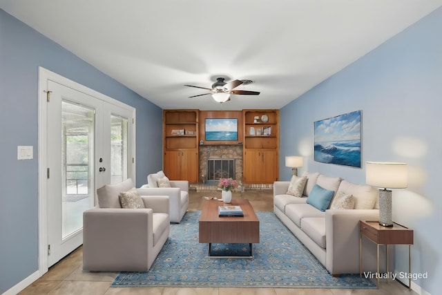 tiled living area featuring a fireplace with raised hearth, a ceiling fan, baseboards, and built in shelves