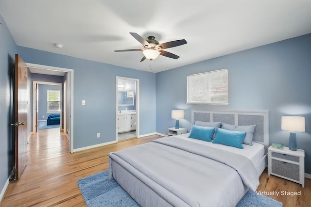 bedroom with light wood-type flooring, ceiling fan, ensuite bath, and baseboards