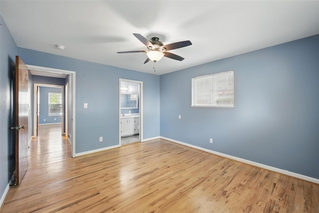 unfurnished bedroom with ensuite bathroom, ceiling fan, light wood-style flooring, and baseboards