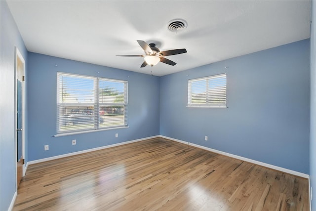 unfurnished room with visible vents, ceiling fan, a wealth of natural light, and wood finished floors