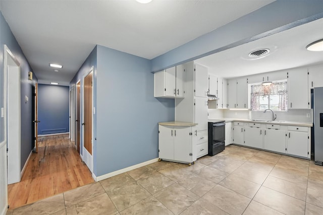 kitchen with a sink, black / electric stove, visible vents, stainless steel refrigerator with ice dispenser, and light countertops