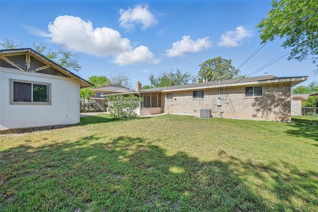 back of property with a sunroom, brick siding, a yard, and central air condition unit