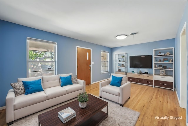 living room with baseboards, light wood-style floors, and built in features