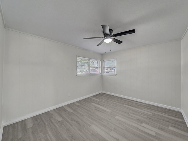empty room with ceiling fan, wood finished floors, and baseboards