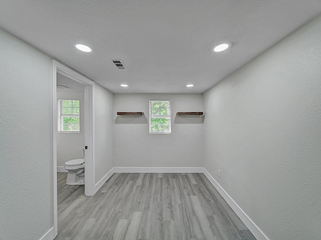 basement with plenty of natural light, visible vents, baseboards, and wood finished floors
