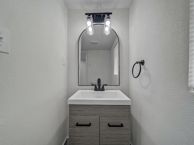 bathroom featuring vanity, a textured wall, and visible vents