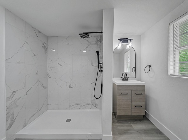 full bathroom with vanity, baseboards, a marble finish shower, and wood finished floors