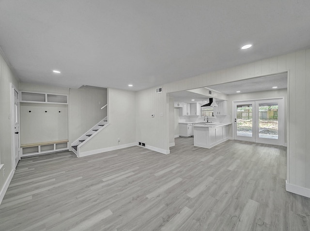 unfurnished living room with a sink, baseboards, and light wood-type flooring