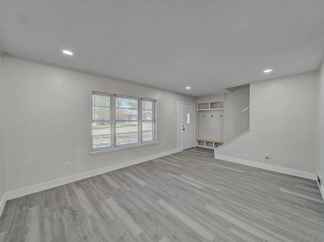 unfurnished living room with baseboards, wood finished floors, and recessed lighting