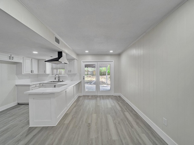 kitchen with a peninsula, visible vents, extractor fan, light wood finished floors, and baseboards