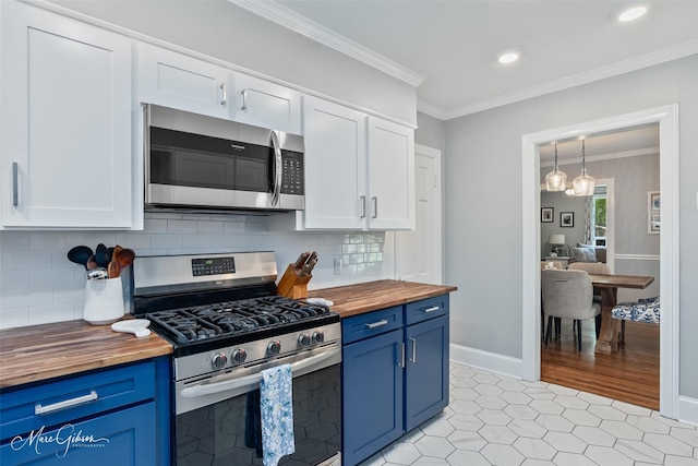 kitchen with crown molding, blue cabinetry, white cabinets, stainless steel appliances, and butcher block countertops