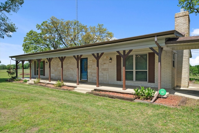 single story home featuring a porch, a chimney, a front lawn, and brick siding