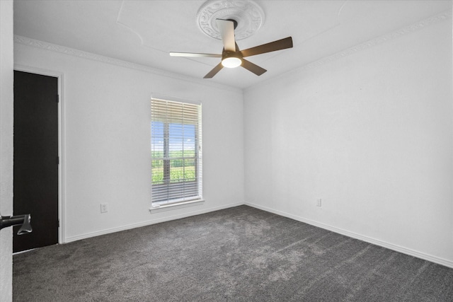 spare room featuring dark colored carpet, baseboards, crown molding, and ceiling fan